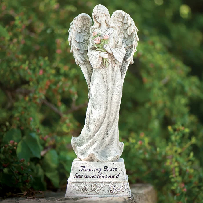 Statue of an angel holding flowers with a blurred green background