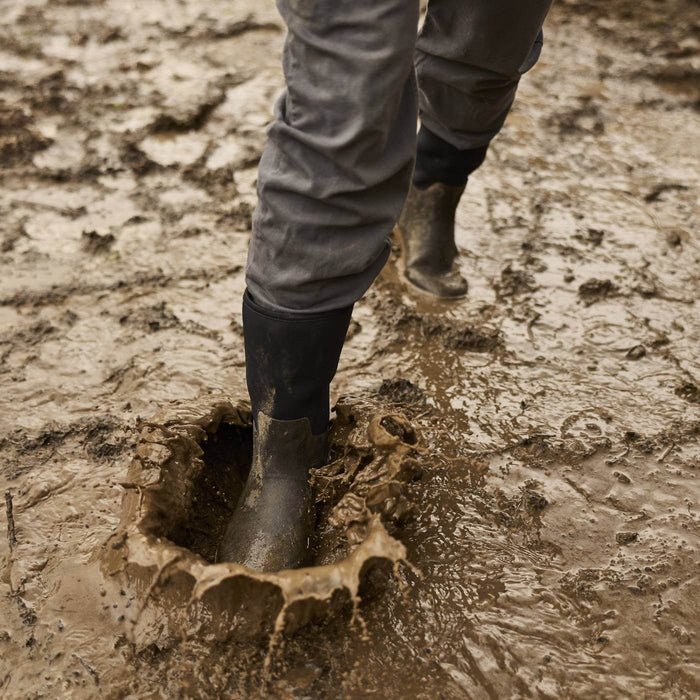 MXP12M00 Person walking through muddy puddle wearing Xplorer 12" Men's Short Outdoor Boots.