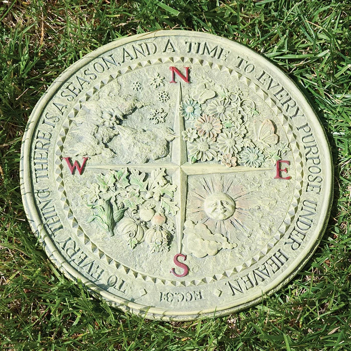 Decorative compass stone with floral designs and text on grass