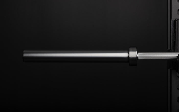 Close-up view of the ribbed sleeve of a racked REP 20kg Alpine Weightlifting Bar.