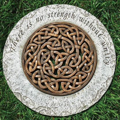Decorative stone with Celtic knot design and engraved text on grass