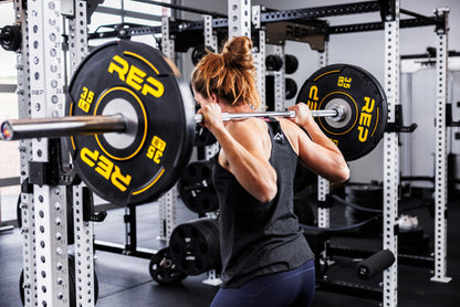 3/4 View: Athlete unracks a Colorado Bar loaded with 35 lb REP Sport Plates 2.0 on their shoulders from a PR-5000 Power Rack
