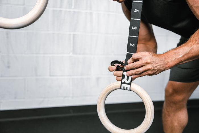 Athlete attaching a Wood Ring to the REP Competition Gymnastic Straps
