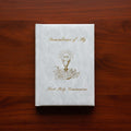 White book titled 'Remembrance of My First Holy Communion' on a wooden surface