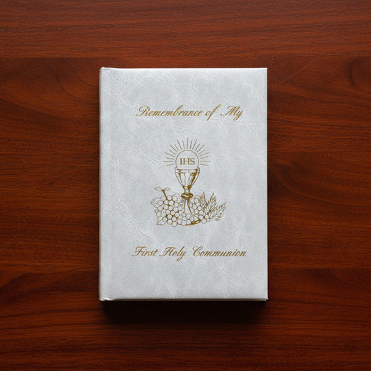 White book titled 'Remembrance of My First Holy Communion' on a wooden surface