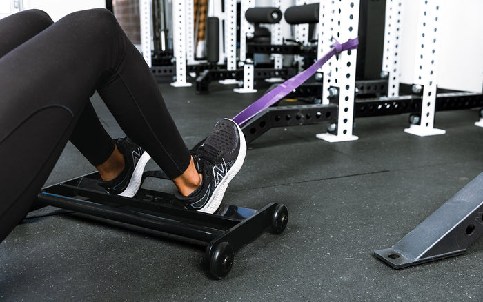 Athlete using glute ham roller with bands attached to a rack