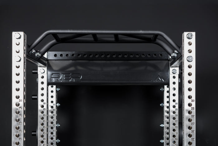 Close up of the stamped Logo Plate Crossmember 2.0 on a REP power rack in front of a black background