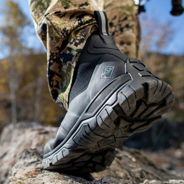 Black hiking boot on a rocky surface with a blurred natural background