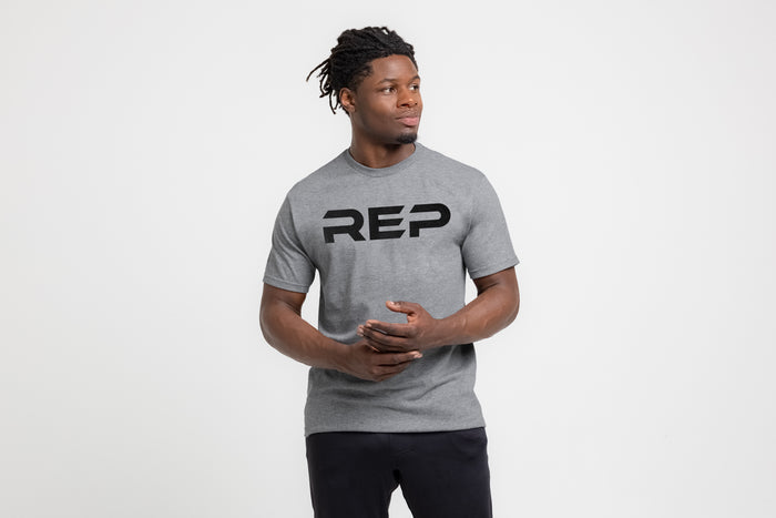 The REP Fitness Men's Bulk Up Heavyweight Crew T-Shirt in Heather Gray/Black front, hands clasped