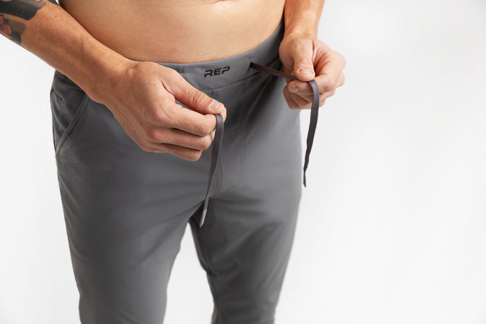 The REP Fitness Men's Felix Pants 2.0 in Cool Gray front, drawstring detail