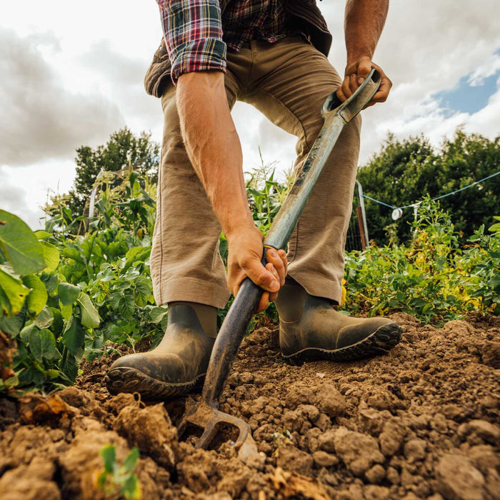 Person gardening with a tool in a field wearing M2A300 Muckster II Men's Ankle Muck Boot