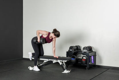 An athlete doing dumbbell rows on a Nighthawk bench with the Quickdraw adjustable dumbbells