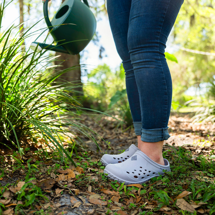 Muckster Lite Women’s Clog in Periwinkle MMLCW050 with water drops in a garden.