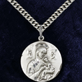 Silver necklace with a pendant featuring an engraved design on a dark blue background