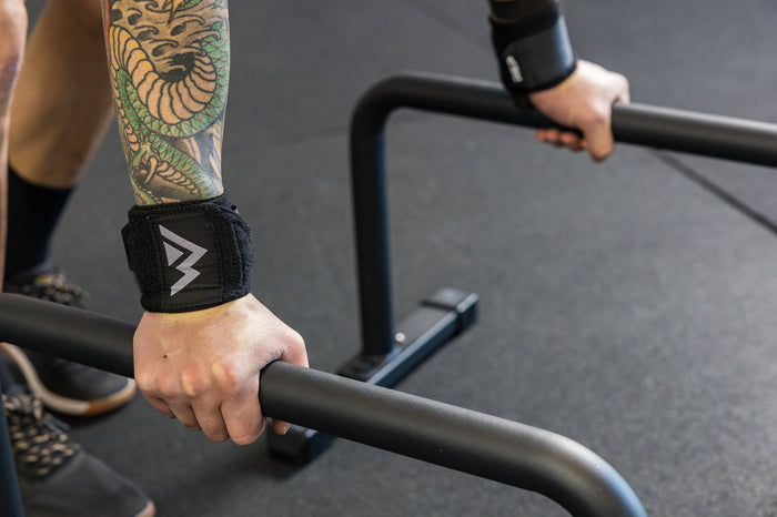 Athlete using wrist wraps with the REP Fitness Parallette Bars
