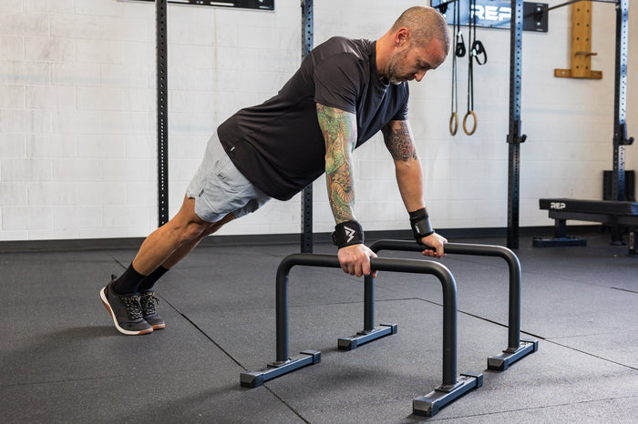 Athlete in an extended push-up position on the REP Fitness Parallette Bars