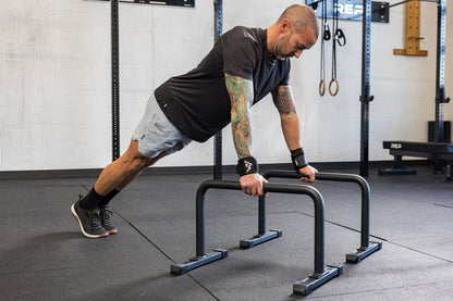 Athlete in an extended push-up position on the REP Fitness Parallette Bars