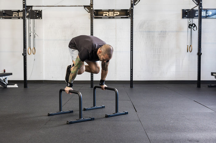 Athlete doing a knee tuck on the REP Fitness Parallette Bars