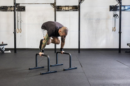 Athlete doing a knee tuck on the REP Fitness Parallette Bars