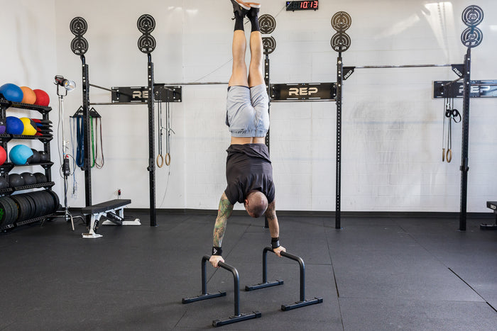 Athlete performing a handstand on the REP Fitness Parallette Bars