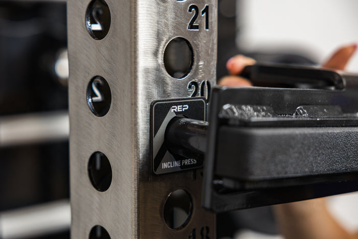 Close-up of an athlete attaching a J-cup to a rack upright over the front squat Power Rack Magnetic Position Marker