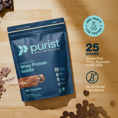 Purist grass-fed whey protein isolate milk chocolate package on a wooden surface with chocolate pieces.