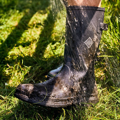 Black rubber boot splashing in water on a grassy background