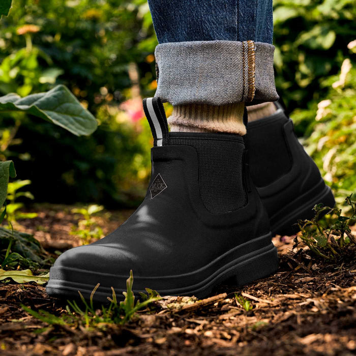 Black rubber rain boots worn outdoors in a garden setting