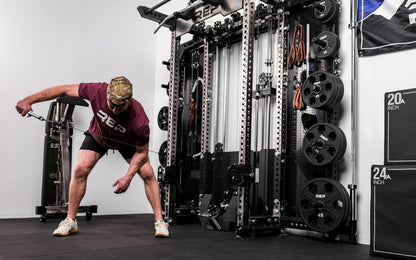 An athlete using the REP® x Kleva Built® ISO Pushdown Grip Cable Attachment to perform bent over tricep kickbacks