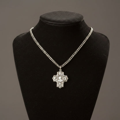 Silver chain necklace with a cross pendant on a black mannequin bust against a gray background