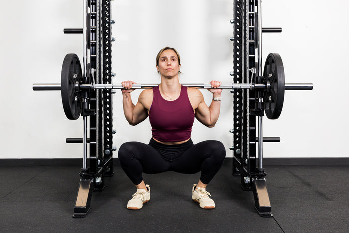Athlete squatting on the front of a rack mounted Smith Machine