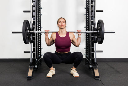 Athlete squatting on the front of a rack mounted Smith Machine