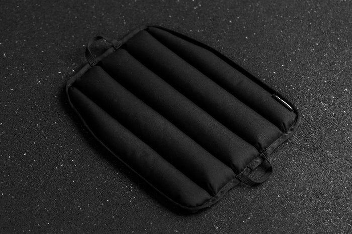 Black soft weight vest plate with ribbed texture on a dark textured background