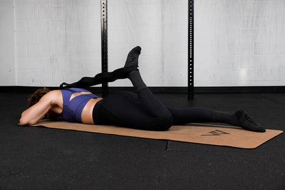 Person lying on a mat with stretching band in a gym setting
