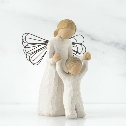 A figurine of a guardian angel, with a resin and metal construction, depicted in a praying posture alongside a child.