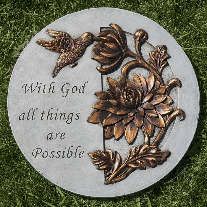 Decorative stone with floral design and 'With God all things are Possible' text on grass