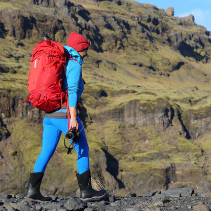 Person hiking in a mountainous landscape with a red backpack