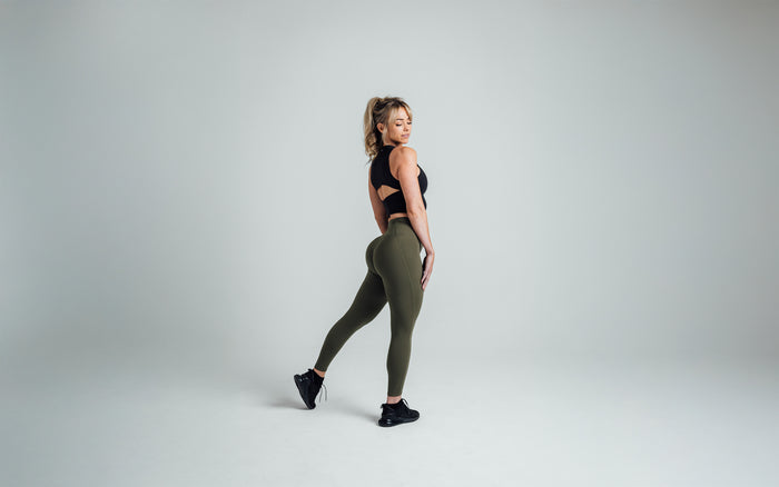 The REP Fitness Women's Rhea Cropped Tank Top in Black back, striking a pose