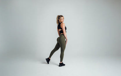 The REP Fitness Women's Rhea Cropped Tank Top in Black back, striking a pose