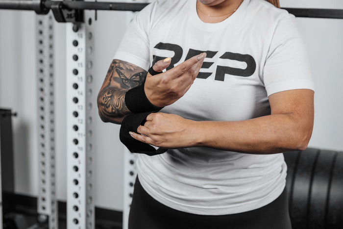 Close up shot of an athlete securing the hook and loop closure of the REP Wrist Wrap around their wrist for a secure fit
