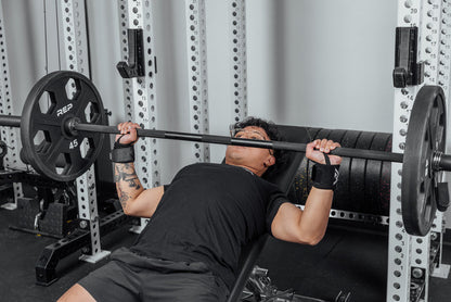 Front shot of an athlete's wrists being supported by the REP Wrist Wraps while pressing a loaded barbell