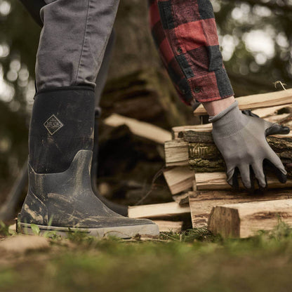 MXP12M00  Person wearing Xplorer Men's Short Waterproof  Rubber Outdoor and a plaid shirt, stacking firewood outdoors.