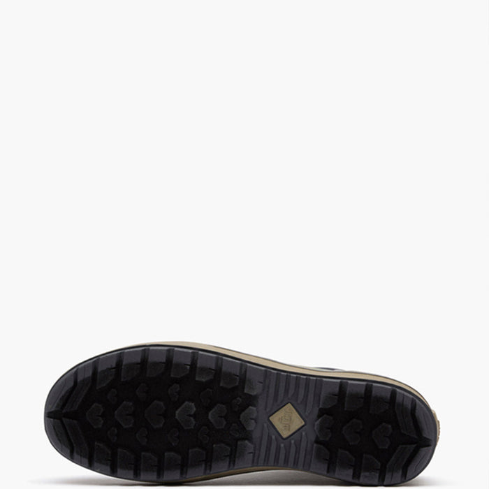 The bottom sole of a black outdoor boot, showing a deep tread pattern and a small tan diamond-shaped logo, set against a plain white background.