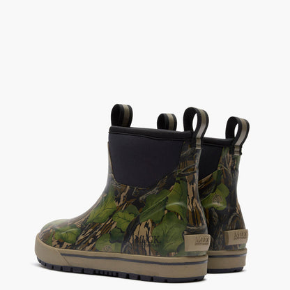 A pair of Muck boots featuring a green and brown woodland camouflage pattern, black elastic side panels, and tan soles, shown against a plain white background.